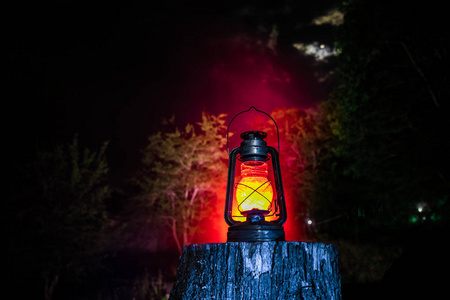 恐怖万圣节的概念。 晚上在森林里烧旧油灯。 噩梦场景的夜景。 选择性聚焦。