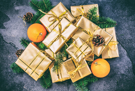 圣诞背景。 金色礼品盒和圣诞装饰橘子，圣诞树，树枝和圆锥形的石板背景。 平躺顶部视图。