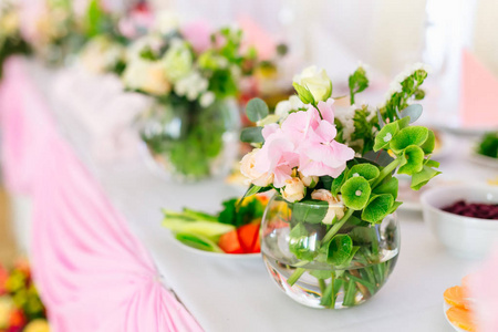 一个圆形的透明花瓶，桌子上放着鲜花和绿色的树枝，上面有美味的菜肴