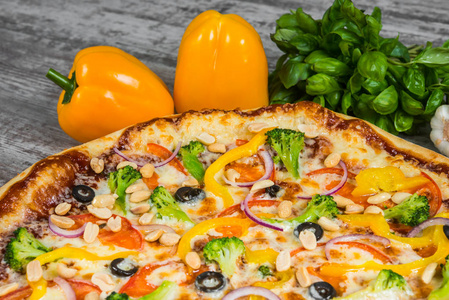 意大利比萨饼在浅木桌上，背景是蔬菜和蔬菜