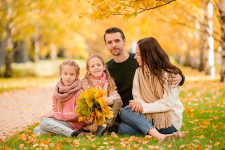 阳光明媚的一天，有小孩的年轻家庭在秋天的公园里。 家庭秋景