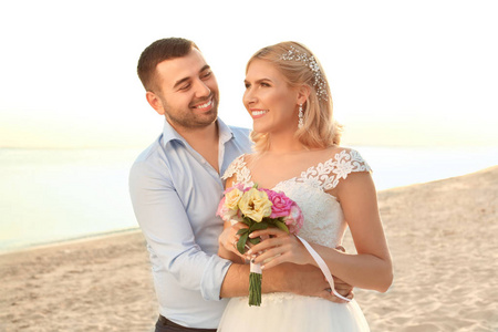 新婚夫妇。 日落时分，新娘和新郎拥抱在沙滩上