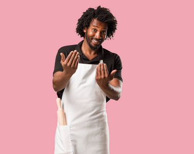 英俊的非裔美国面包师邀请来自信和微笑，做一个手势，用手积极和友好