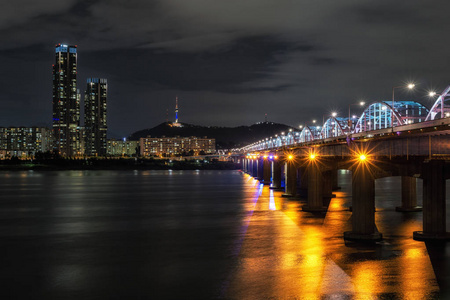 东贾克桥越过汉江和著名的地标南三塔在远处拍摄的夜晚。韩国首尔