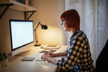 一名年轻女性在家电脑上工作的照片。