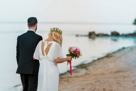 婚礼情侣的后景，花束漫步在海滩上