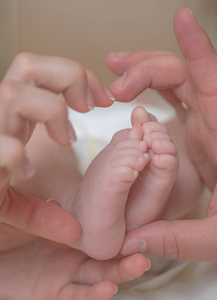 爱。 新生婴儿。 可爱的婴儿腿在父母手里。 婴儿的脚在妈妈手里。 妈妈和孩子。 幸福的家庭观念。 美丽的母性概念形象。 新生儿的