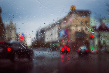 在汽车挡风玻璃上看到雨水滴落的城市道路