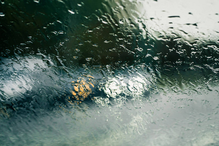 在汽车挡风玻璃上看到雨水滴落的城市道路