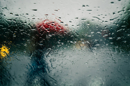 在汽车挡风玻璃上看到雨水滴落的城市道路