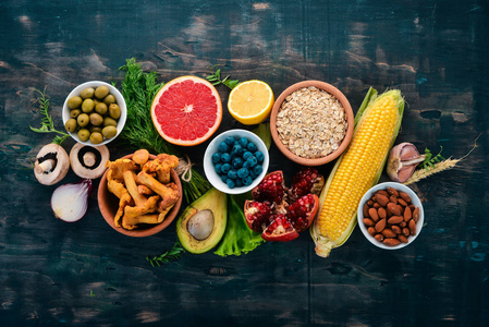 健康食品清洁饮食选择蔬菜，水果，坚果，浆果和蘑菇，欧芹，香料。在黑色的背景上。免费的文本空间。