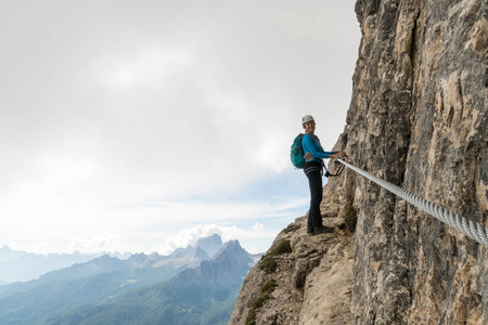 年轻迷人的女登山者，在陡峭的陡峭和暴露通过费拉塔在阿尔塔巴迪亚在意大利白云岩的南部蒂罗尔
