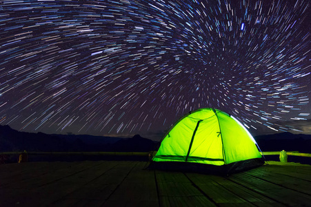 发光的绿色露营帐篷在竹台上，夜空下充满了星星和银河系Baan JaboMae HongSon泰国。 休闲游客。