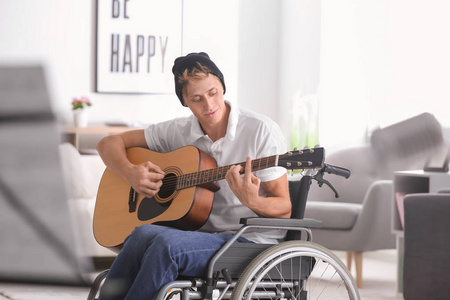 坐轮椅的年轻音乐家在家弹吉他