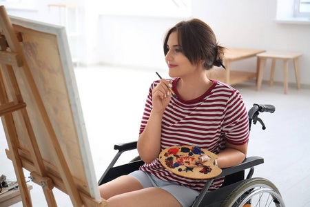 坐轮椅的年轻女画家在家中画