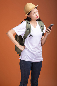 年轻的时髦游客使用手机。 戴着背包帽子的亚洲女人看着手机。 迷惑情绪。 希普斯特度假的概念。