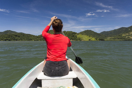 巴西里约热内卢南部热带雨林中的年轻女子，身穿红色衬衫，在海洋皮划艇