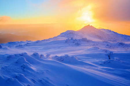 日出启示天空山和树木站在雪堆上，覆盖着冰冻的雪，黄色的光芒。