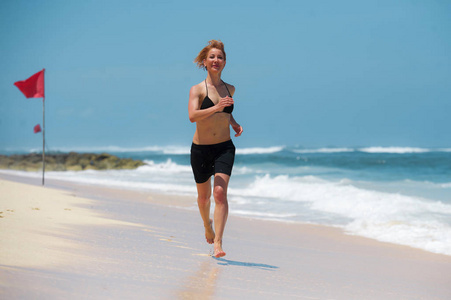 年轻有魅力快乐的女人在热带天堂海滩上奔跑，沙滩洁白生动的绿松石海色，赤脚慢跑，在健身假日微笑，健康的生活方式理念