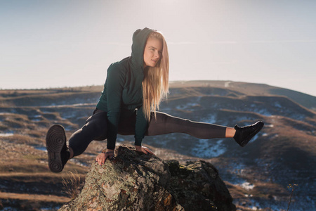 年轻的健身妇女在山顶上锻炼