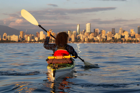 女孩海上皮划艇在市中心前，在一个充满活力的阳光明媚的夏季日落。 摄于加拿大温哥华。