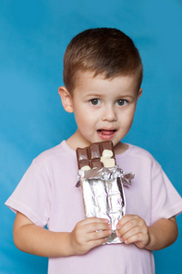 可爱的小男孩吃巧克力棒。 非常可爱的孩子与巧克力隔离。 快乐男孩巧克力棒