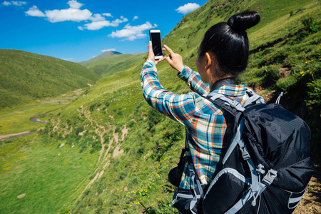 高空草原山区女徒步旅行者用手机拍照