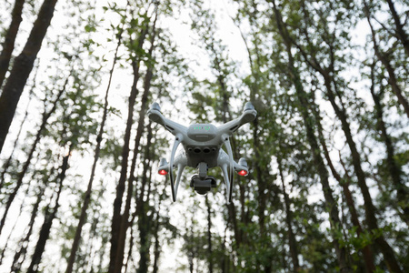带摄像机的白色无人机飞在热带森林