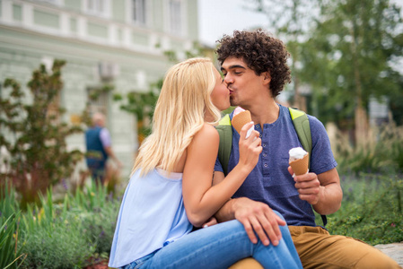 一对年轻夫妇在户外吃冰淇淋和接吻的肖像。