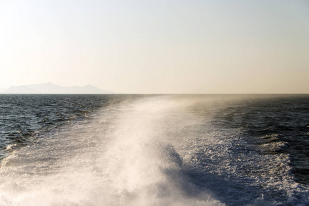 日落时双体船引起的海水飞溅和海浪