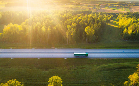 高速公路上的卡车。 卡车在晚上上路。 货物运输背景。 货物运输。 有卡车的道路在阳光和阳光下。