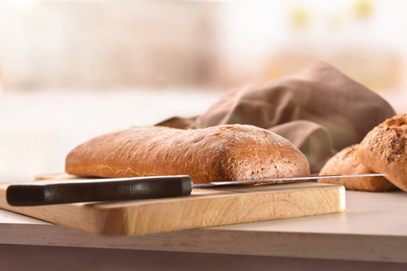 厨房长凳上的砧板上的一整条面包。 前面的风景。 水平组成部分