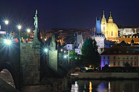 著名的查尔斯桥与马拉斯特拉纳桥塔楼和老镇地标的风景。 圣尼古拉斯教堂在夏夜的背景。 捷克共和国