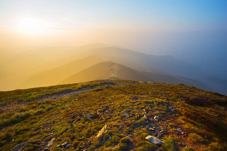 在戏剧性的夕阳下，在薄雾中登上山顶