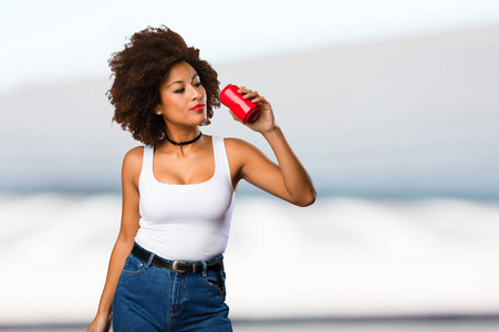 年轻的黑人妇女拿着汽水罐模糊的背景