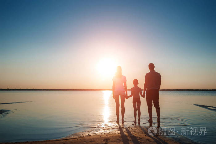 一家人在湖面上迎着美丽的日落. 幸福的生活幸福