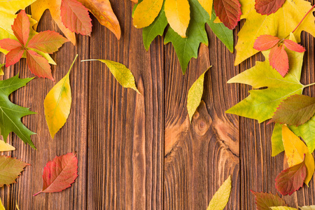 秋天的横幅，在棕色的木制背景上有五颜六色的树叶，自然的秋天框架，树叶和复制空间，供季节性问候或促销水平海报。
