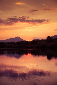 一个美丽的五颜六色的日落，在山上，湖和森林的紫色色调。 抽象的光明景观。 斯洛伐克欧洲的塔特拉山。
