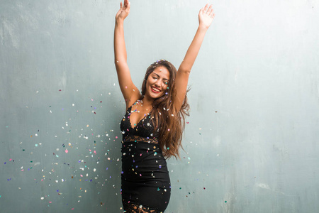 年轻的拉丁女人庆祝新年或活动。 非常高兴和兴奋地举起她的手臂。
