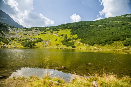 在平静的晴天，山谷里有一个美丽而干净的湖。 夏天有水的山景。 斯洛伐克欧洲的纹身山。