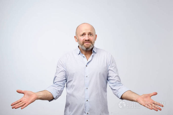 困惑的成熟胡须男人站着,耸着肩膀,孤立在白色的背景上.