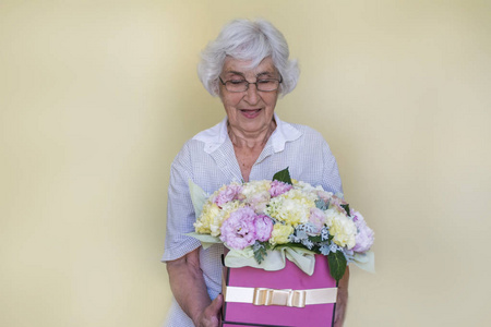 幸福的老妇人拿着粉红色玫瑰花盒，牡丹和绣球花