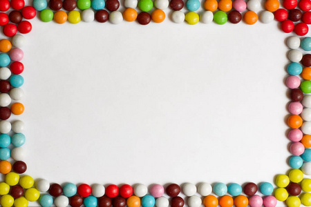 白色背景上覆盖着彩色釉的圆形巧克力棒糖。顶部视图