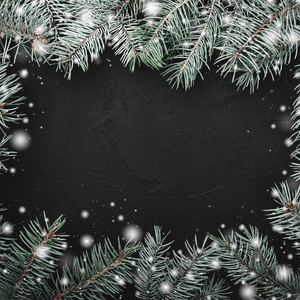 黑色方形石头背景。 冷杉树枝的框架。 雪效应。 文本空间。 顶部视图