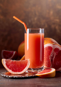 一杯新鲜葡萄柚汁和在旧木桌上切水果。