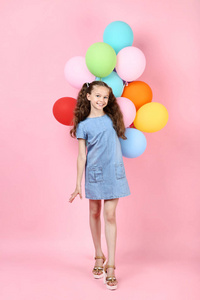 带彩色气球的年轻女孩，粉色背景