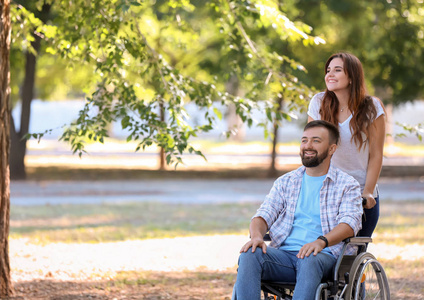 坐轮椅的年轻人和妻子在户外散步