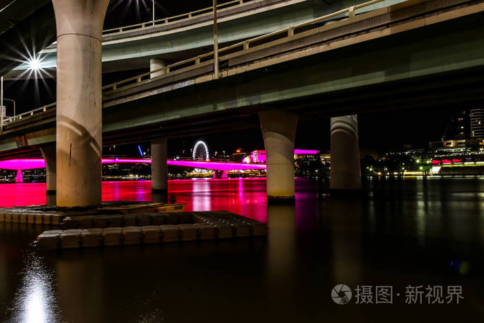 平静的河流漂浮在混凝土桥支架附近,在澳大利亚布里斯班的黑暗夜晚.