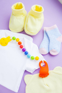 s shoes and toys on purple background. Newborn. Top view