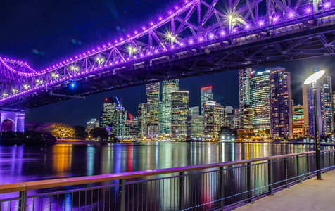在澳大利亚摩天大楼的背景下，在城市河流上方发光明亮的桥下的现代堤坝的城市景观